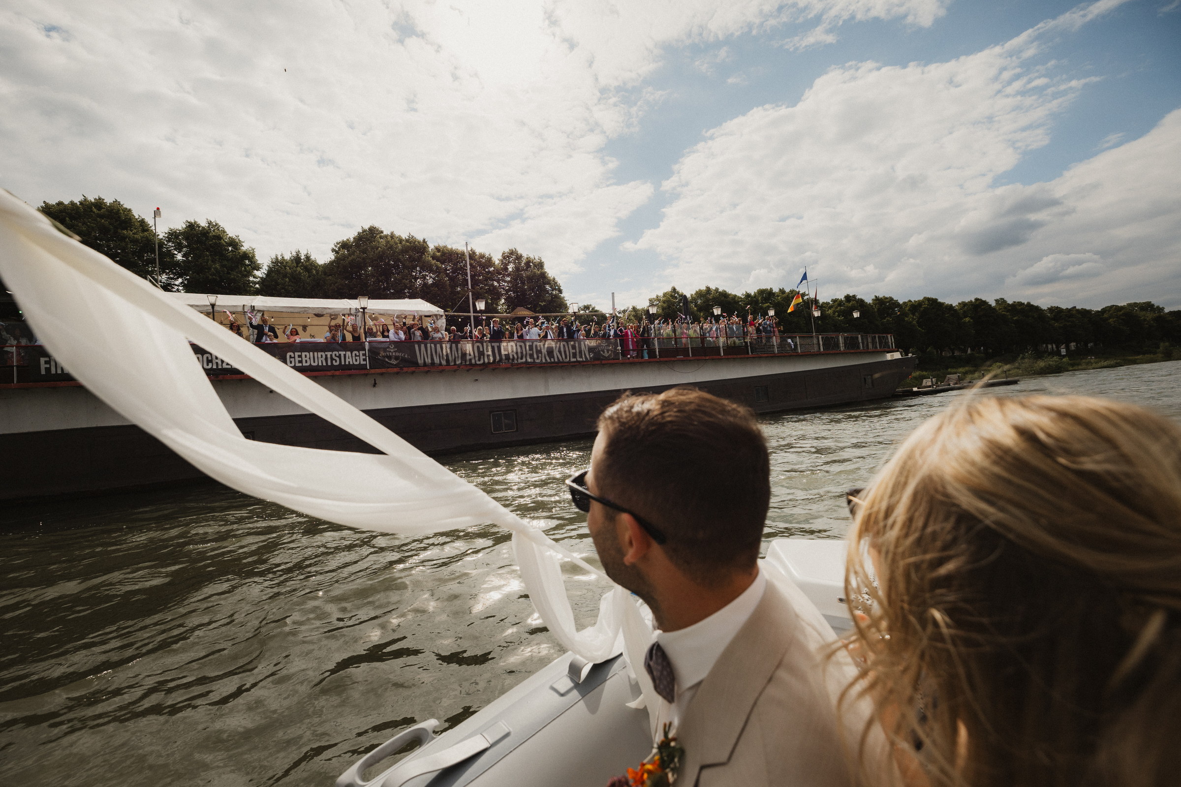 Blick vom Boot auf das Partyschiff Achterdeck, an dessen Reling die Gäste winken