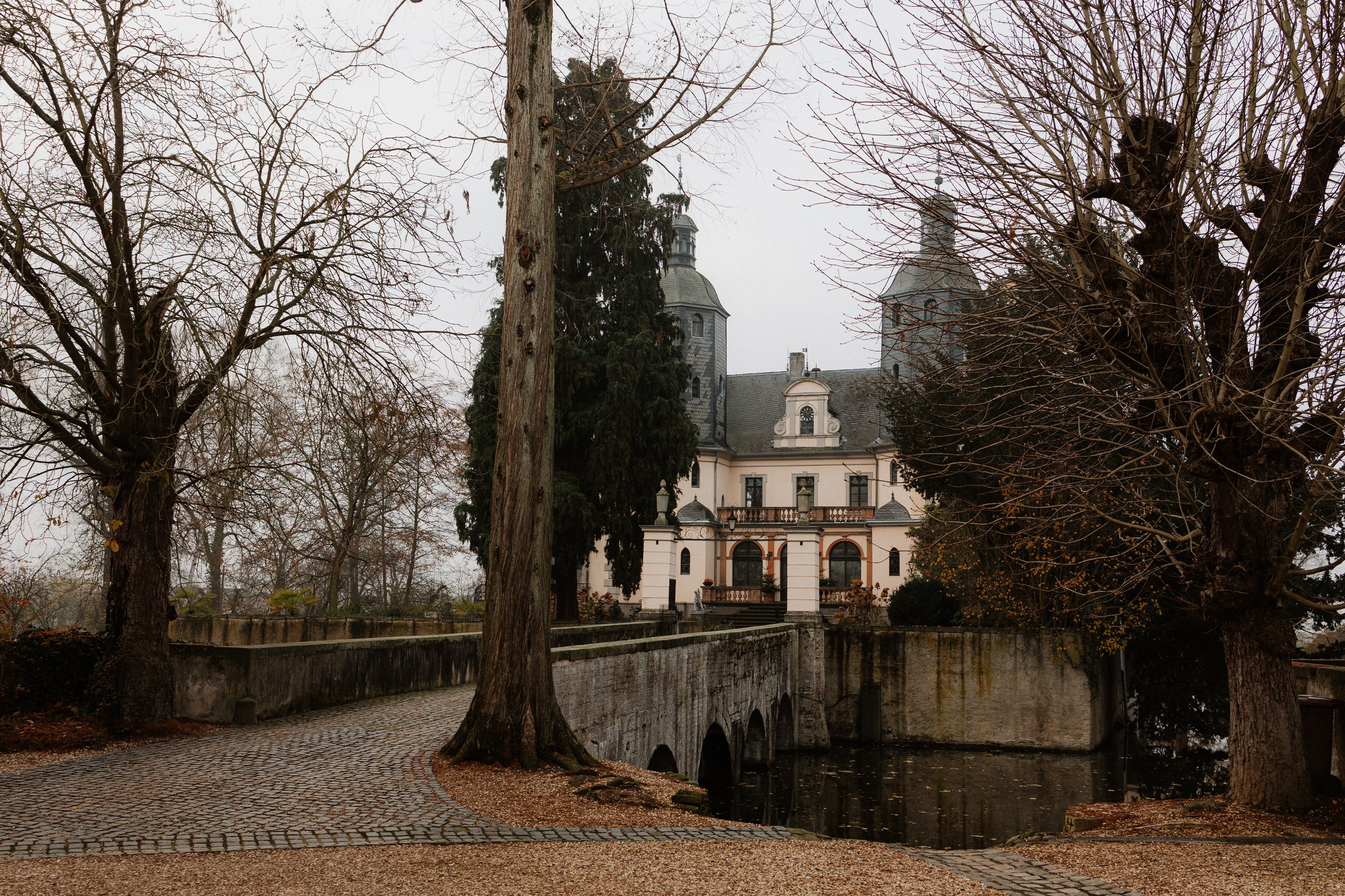 Zufahrt zur Burg Kriegshoven über die Steinbrücke, kahle Bäume im Dezember