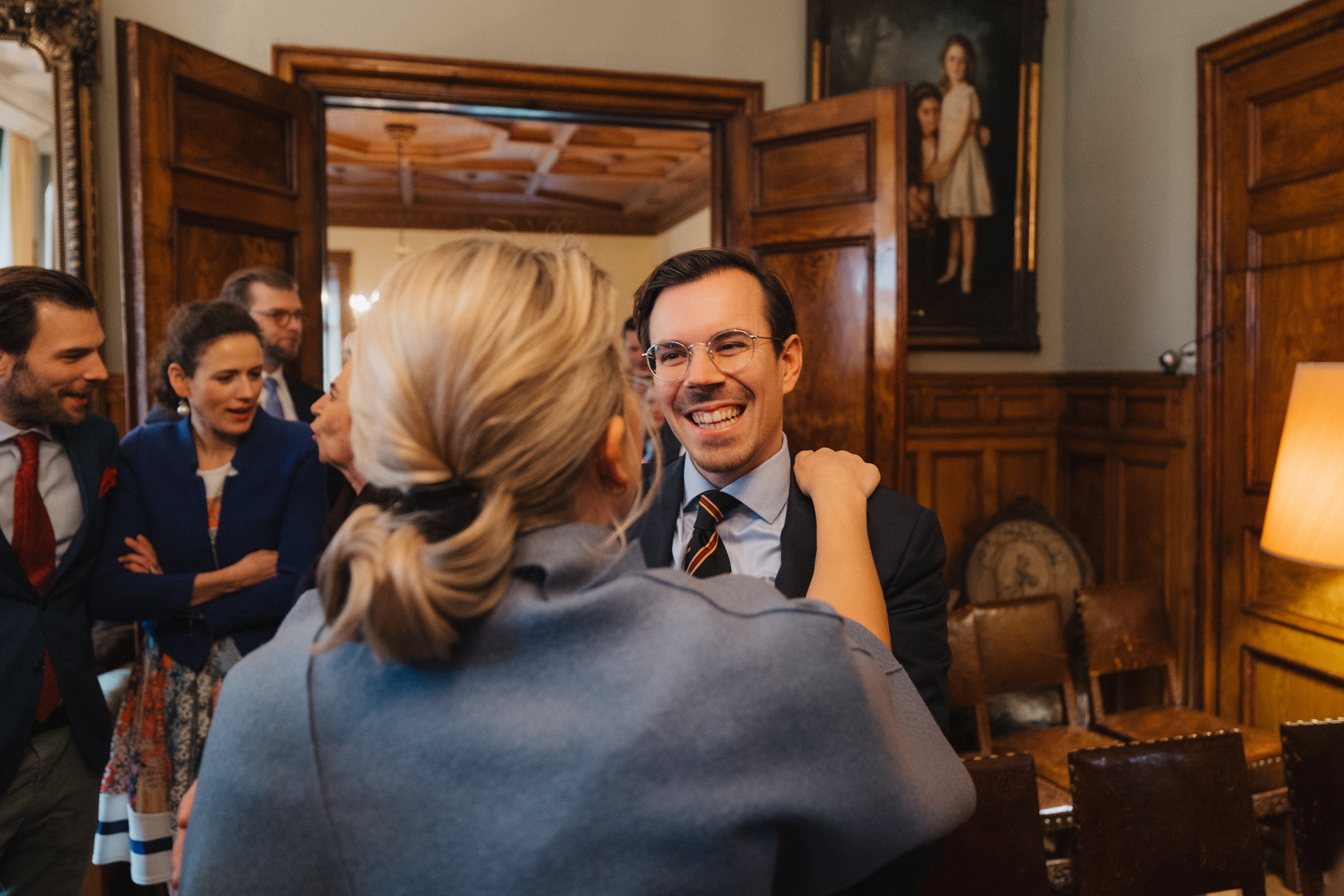 Gast umarmt den Bräutigam zur Gratulation im holzvertäfelten Saal