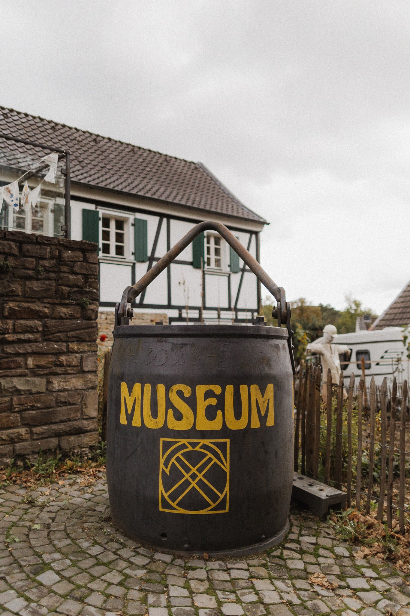 Schwarzes Fass mit gelber Aufschrift Museum vor einem Fachwerkhaus