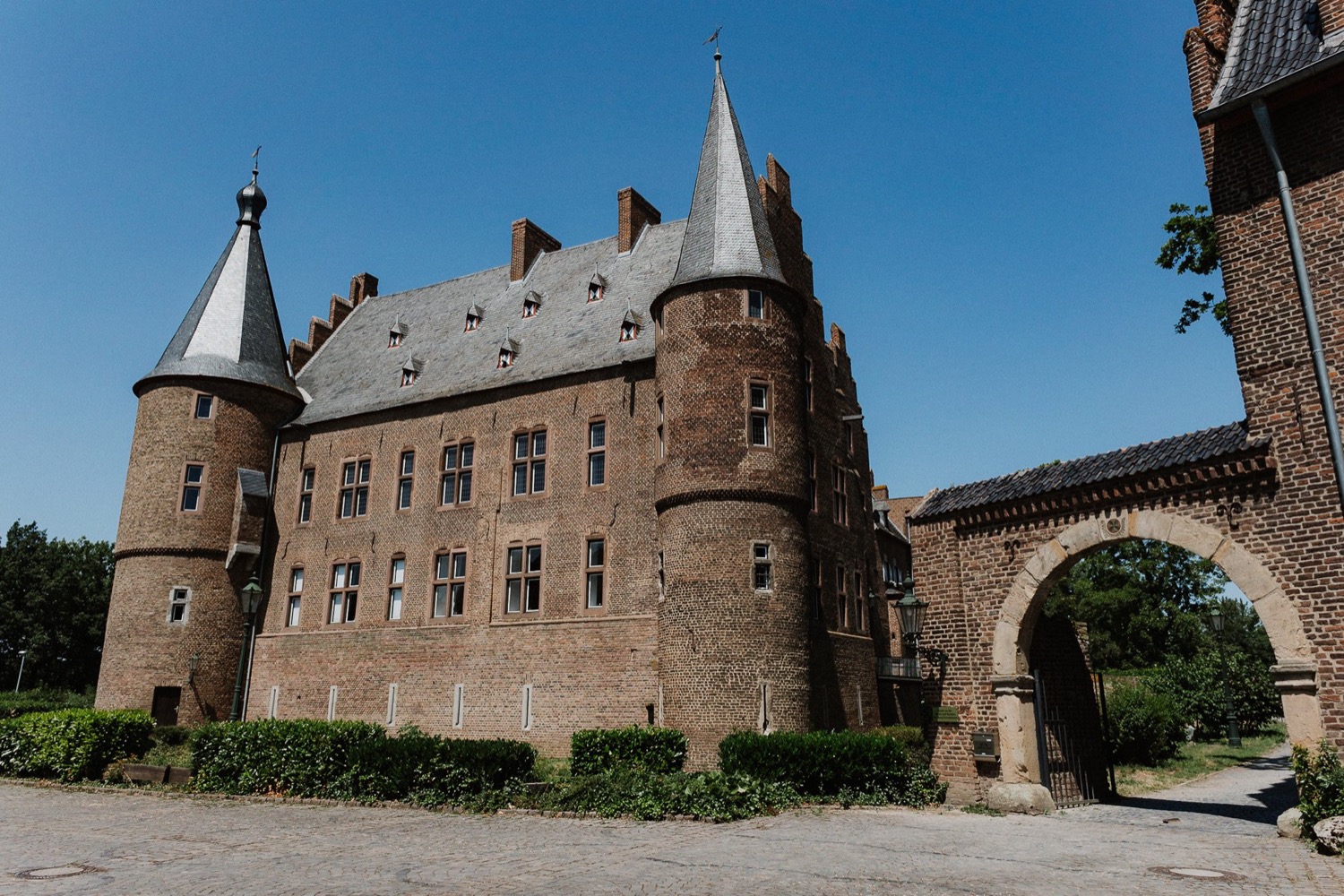 Burg Konradsheim aus Backstein mit zwei Türmen und steinernem Torbogen unter blauem Himmel