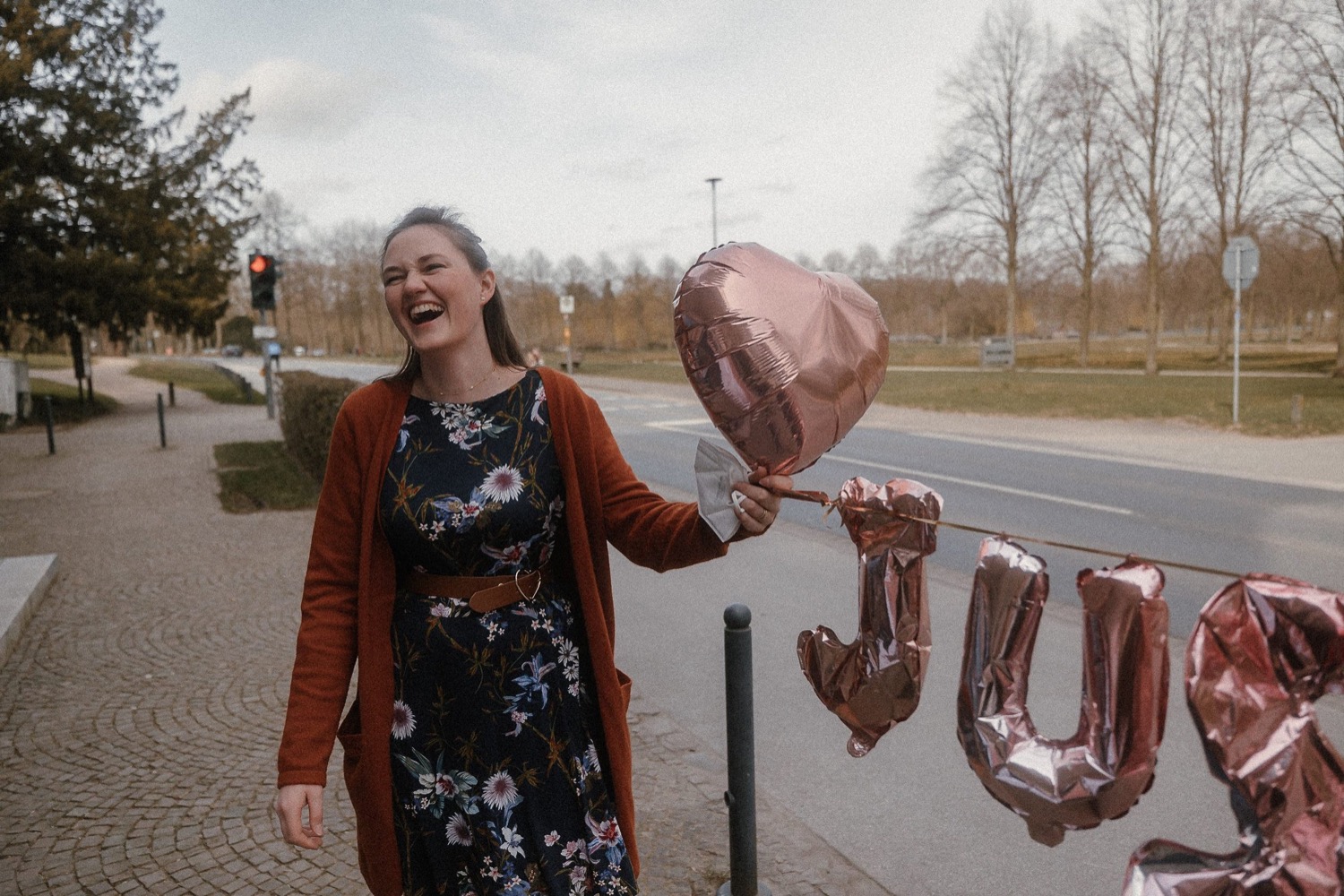 Gast läuft lachend mit herzförmigen Luftballons am Straßenrand