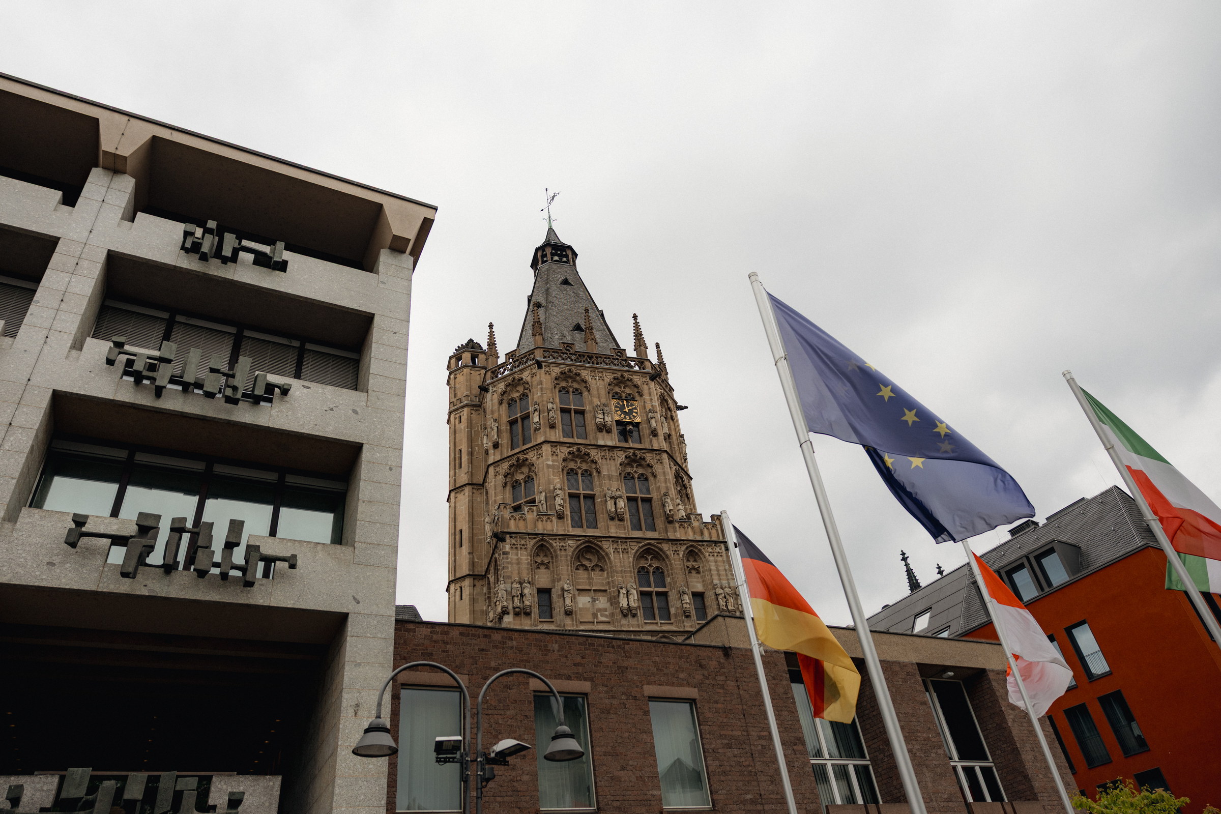Der gotische Rathausturm in Köln neben dem Spanischen Bau, davor wehende Fahnen