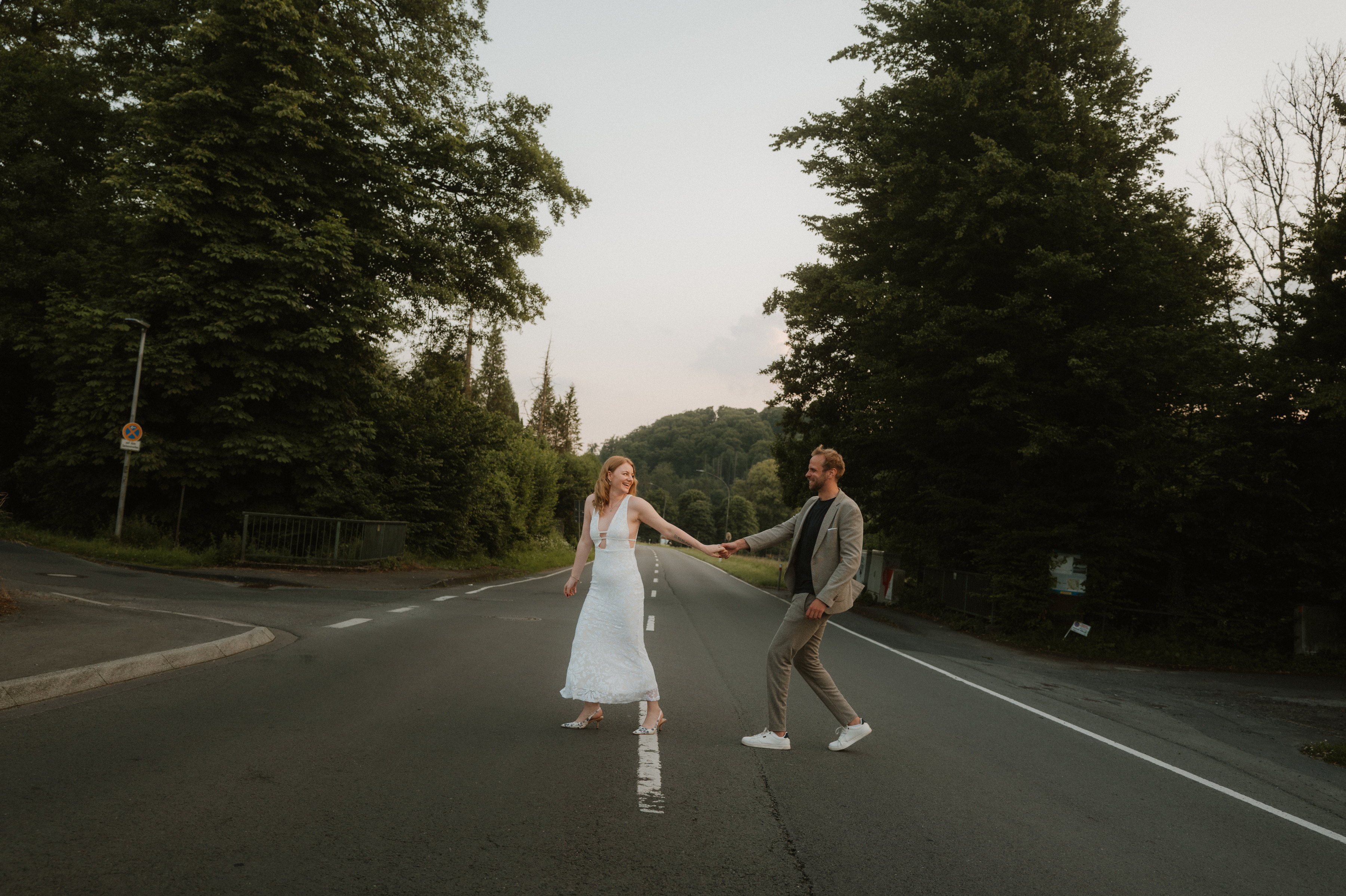 Paar geht Hand in Hand über eine leere Landstraße in der Abenddämmerung