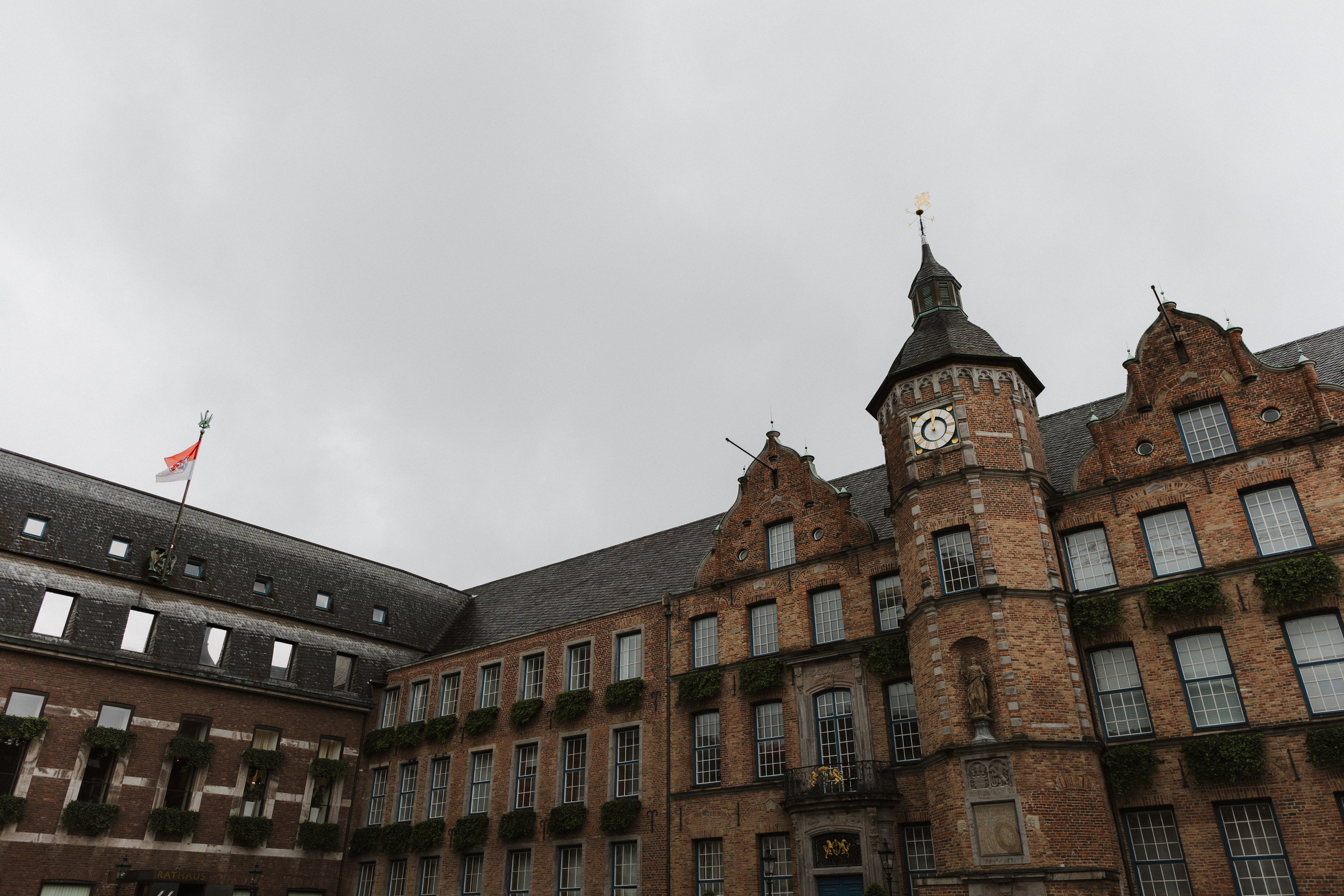 Backsteinfassade des Düsseldorfer Rathauses mit Uhrturm und Stadtwappenfahne